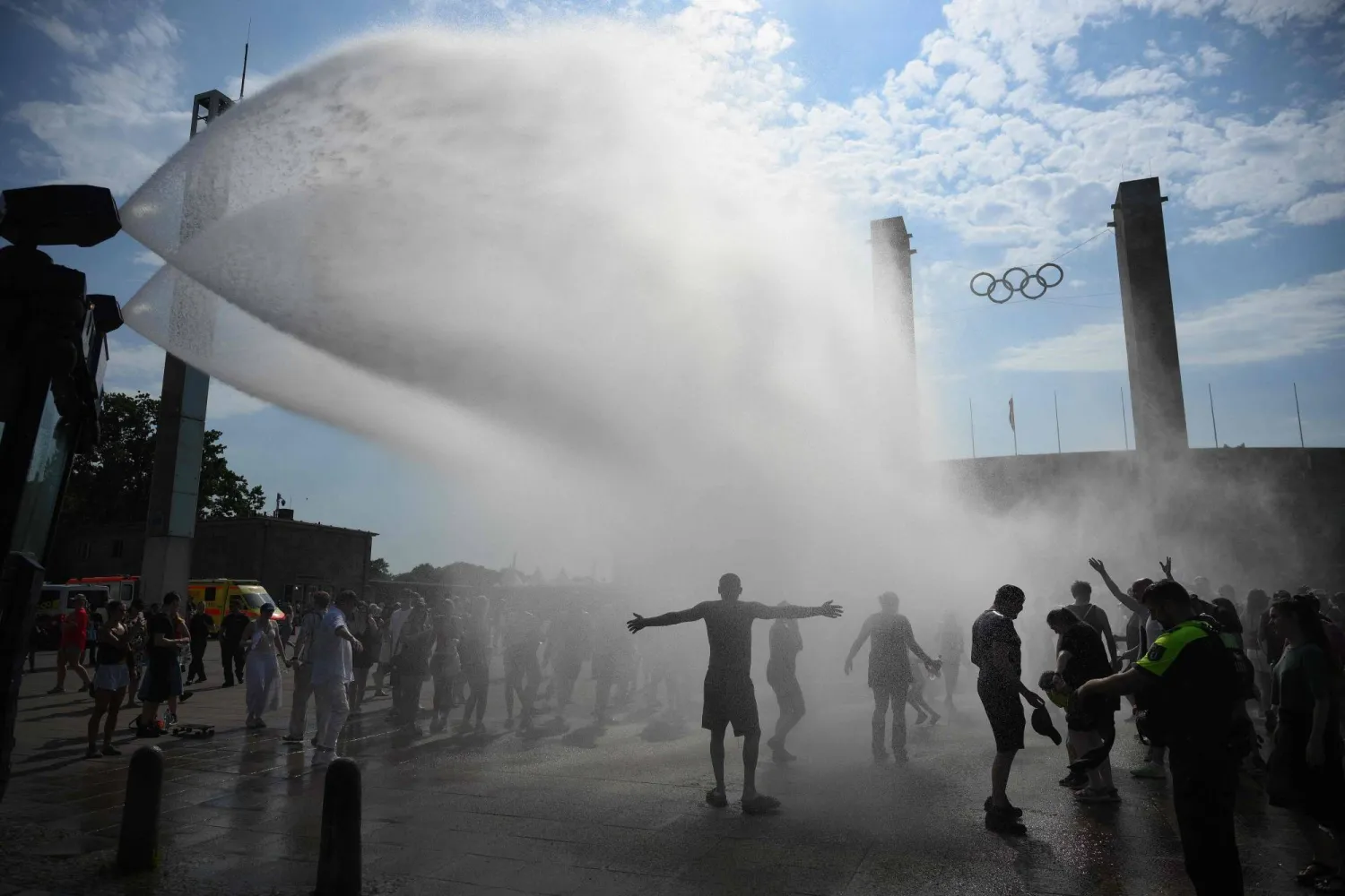 Police use water cannon to spray people with water as the arrive at the Olympic stadium for a concert of US singer Bruno Mars on June 28, 2026, in Berlin, as the German capital is expected to reach temperatures around 40 degrees Celsius during a heatwave in Europe. (AFP)