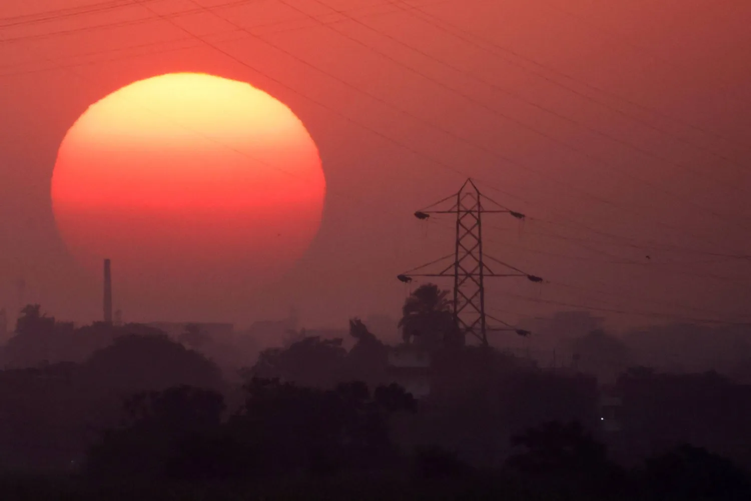 The sun behind high-voltage power lines and electricity pylons along the River Nile during a heatwave in Al-Qanatir al-Khairia, on the outskirts of Cairo, Egypt, July 4, 2026. REUTERS/Amr Abdallah Dalsh