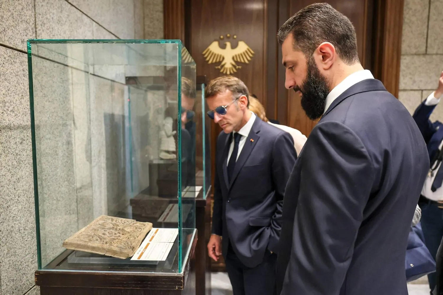 This handout picture released by the official Syrian Arab News Agency (SANA) shows Syria's interim President Ahmed al-Sharaa and France's President Emmanuel Macron inspecting repatriated Syrian artifacts that had been on loan to the Arab World Institute in Paris since 2010, during an official ceremony at the at the People's Palace in Damascus on July 7, 2026. (SANA/AFP)