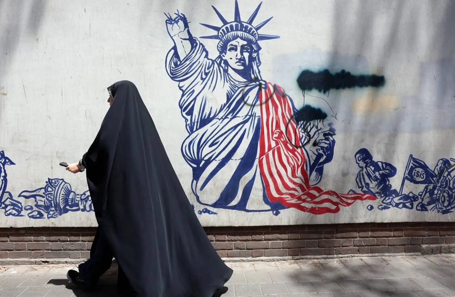 A woman walks past an anti-US mural next to the former US embassy in Tehran, Iran, 09 July 2026. (EPA)