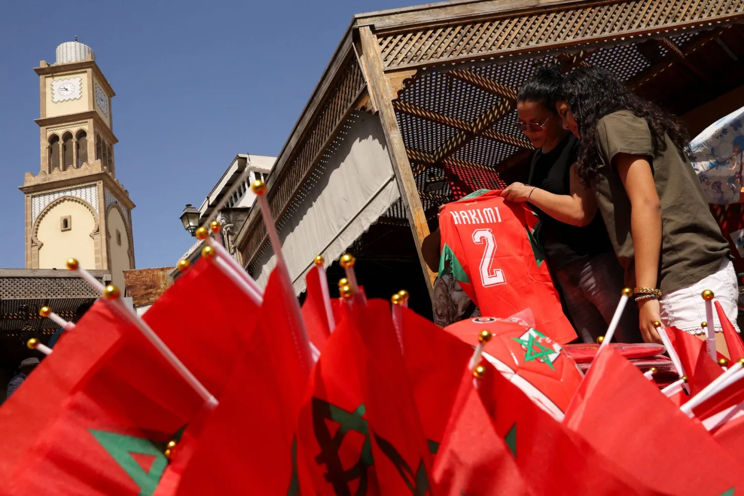 أشخاص يشترون قمصان المنتخب المغربي من بائع متجول في الدار البيضاء قبل مواجهة المغرب وفرنسا (رويترز)