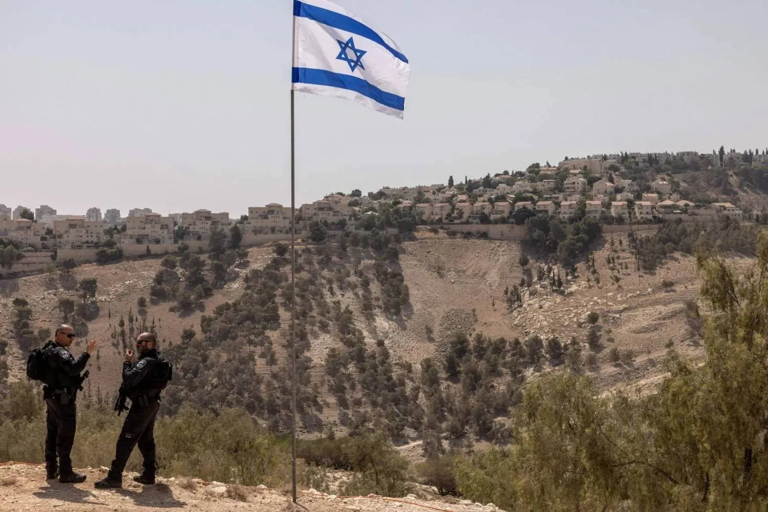 شرطيان إسرائيليان يقفان في منطقة «إي 1» قرب مستوطنة «معاليه أدوميم» خارج القدس بالضفة الغربية (أرشيفية - أ.ف.ب)