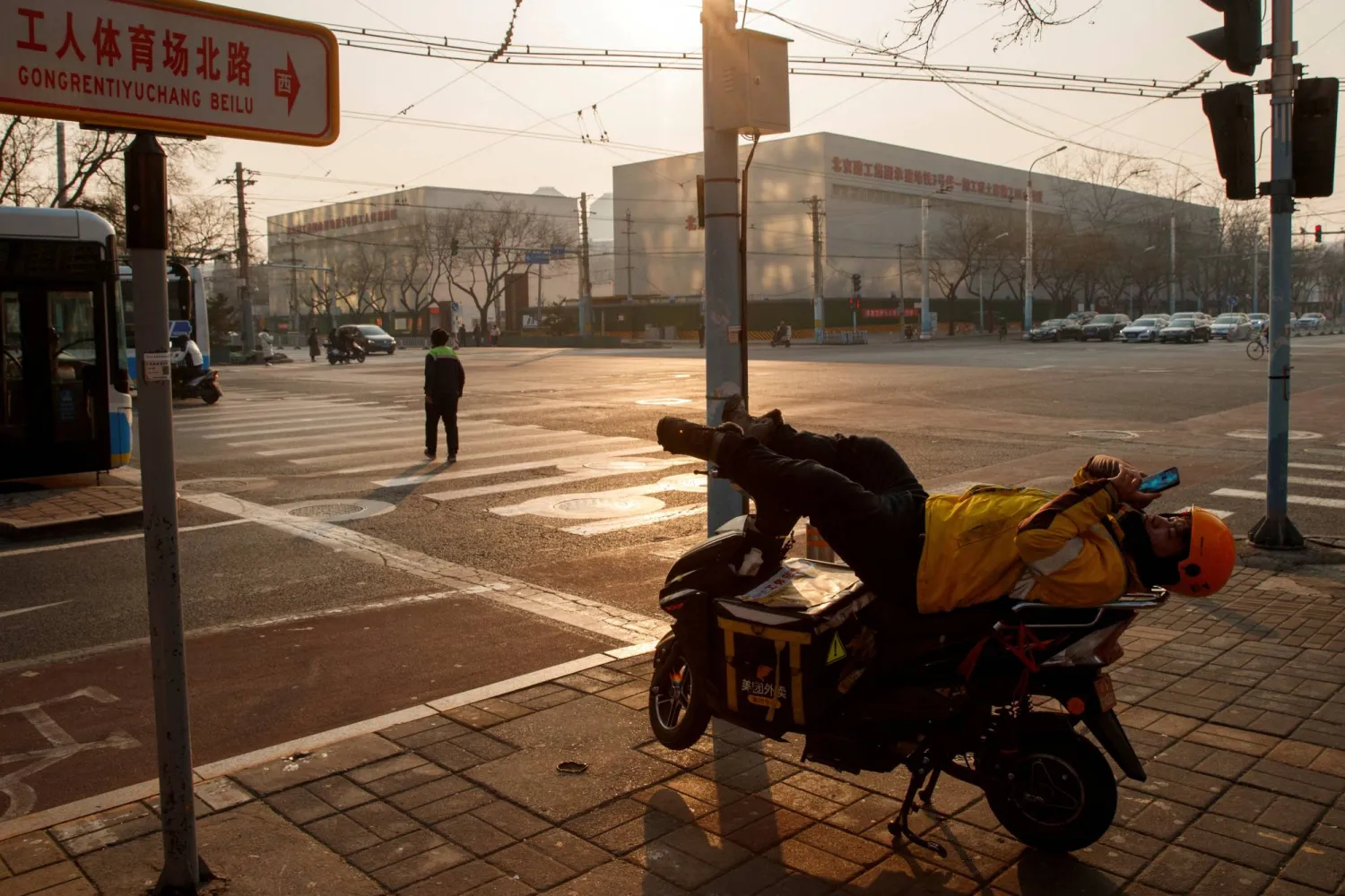 FILE PHOTO: A delivery driver looks at this phone as he rests on his electric bike in Beijing, China January 25, 2020. REUTERS/Thomas Peter