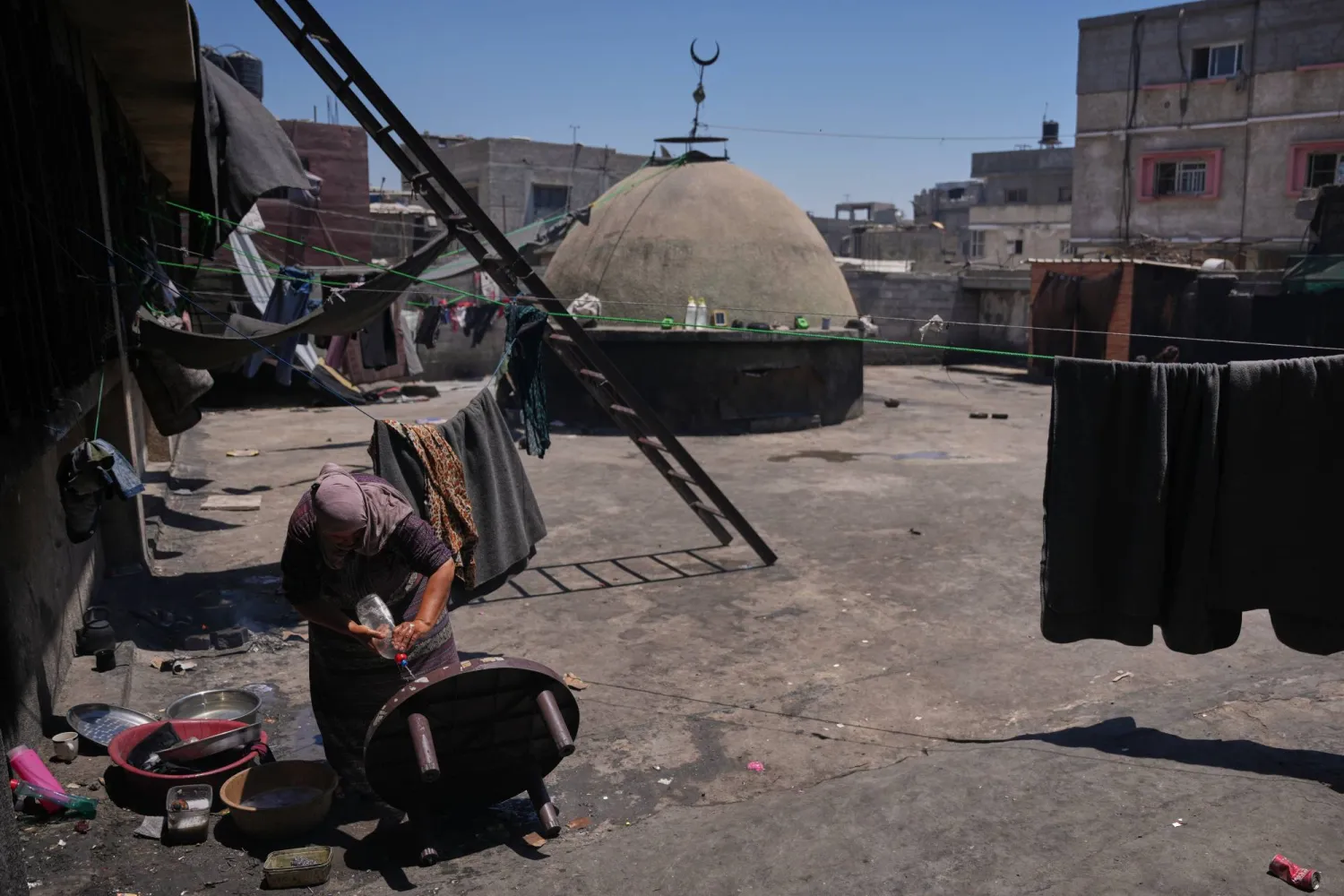فلسطينية تنظف طاولة على سطح مسجد تحول ملجأً لنازحين في خان يونس جنوب قطاع غزة الجمعة (أ.ب)