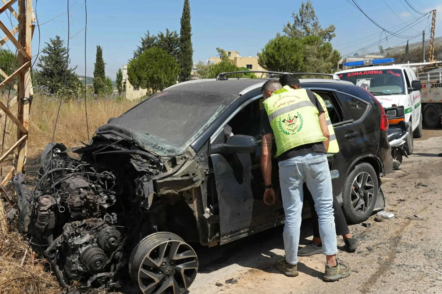 أحد عناصر الدفاع المدني اللبناني يتفقد سيارة استهدفتها غارة إسرائيلية في كفر رمان بجنوب لبنان (أ.ف.ب)