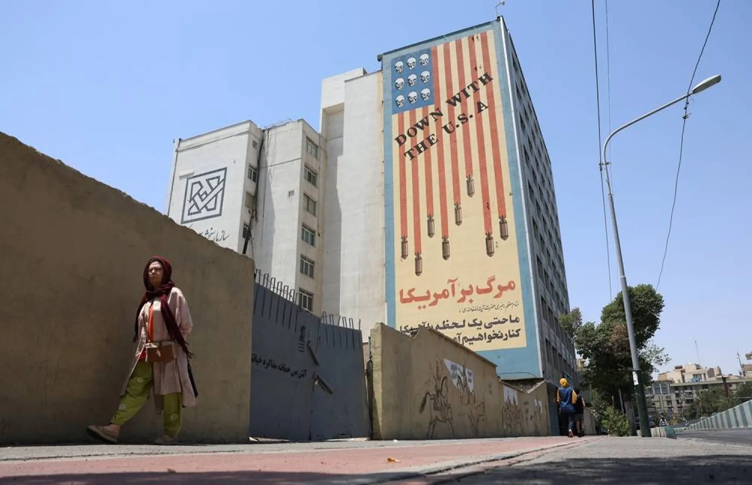 An Iranian woman walks near an anti-US mural in a street in Tehran, Iran, 09 July 2026. (EPA)