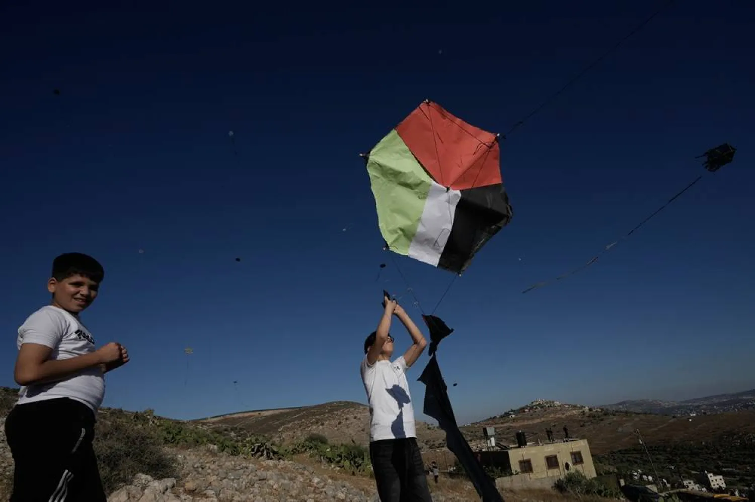  A youth releases a kite in the colors of the Palestinian flag as he takes part in a kite festival under the theme "The Land Is Our Land and the Sky Is Our Sky," in the village of Burin near the West Bank city of Nablus, Friday, July 10, 2026. (AP) 