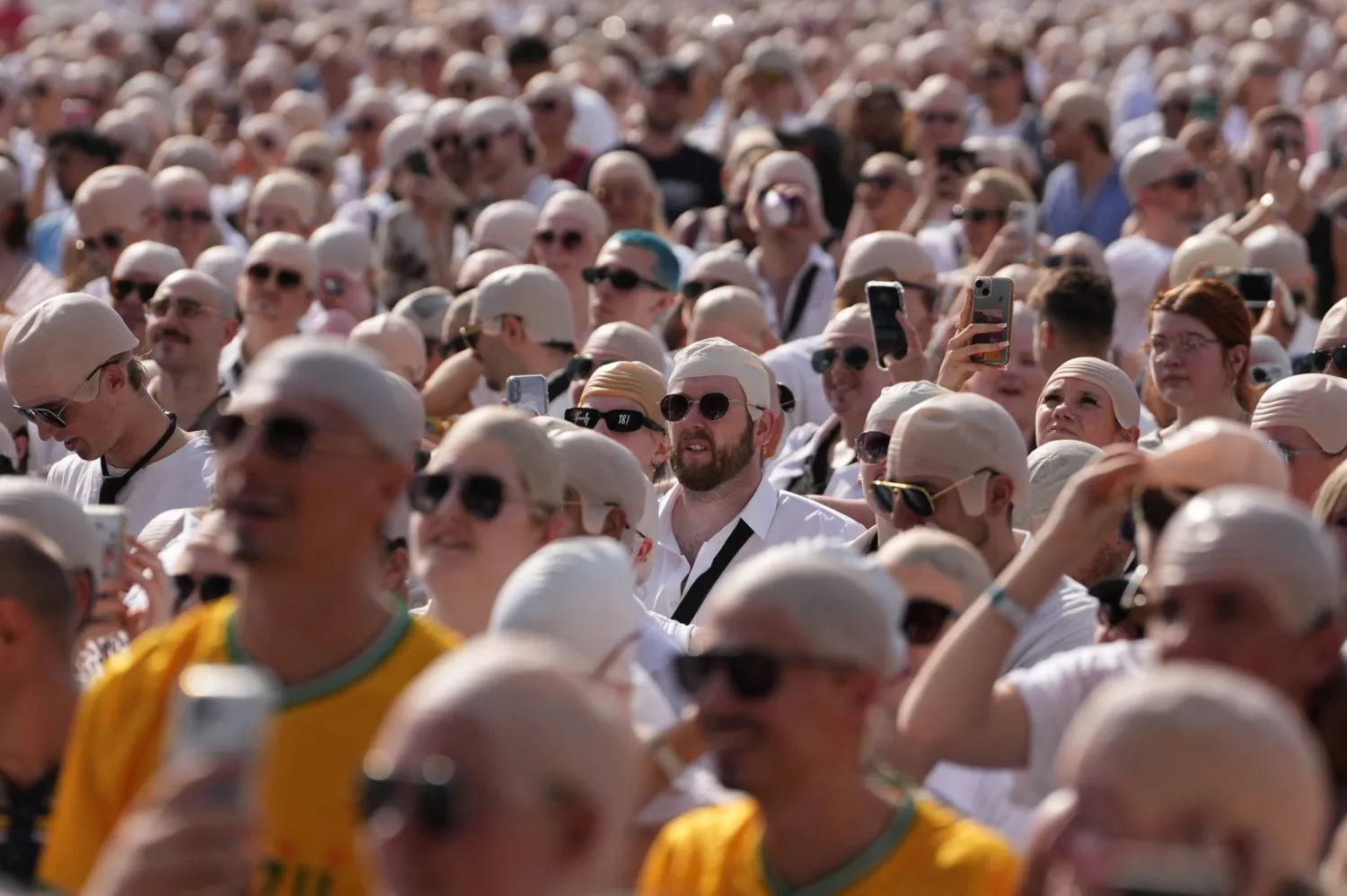 Members of the crowd sporting "bald caps" gather in the sunshine ahead of a concert by US rapper and singer Pitbull in Hyde Park, London, on July 10, 2026. (AFP)