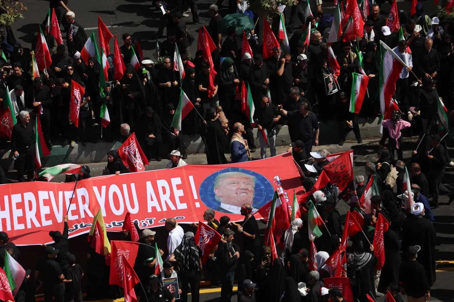 İran’ın eski Dini Lideri Ali Hamaney’in geçtiğimiz hafta Tahran’da düzenlenen cenaze töreninde İranlılar, ABD Başkanı Donald Trump’a yönelik tehdit içeren bir pankart açtı. (EPA)