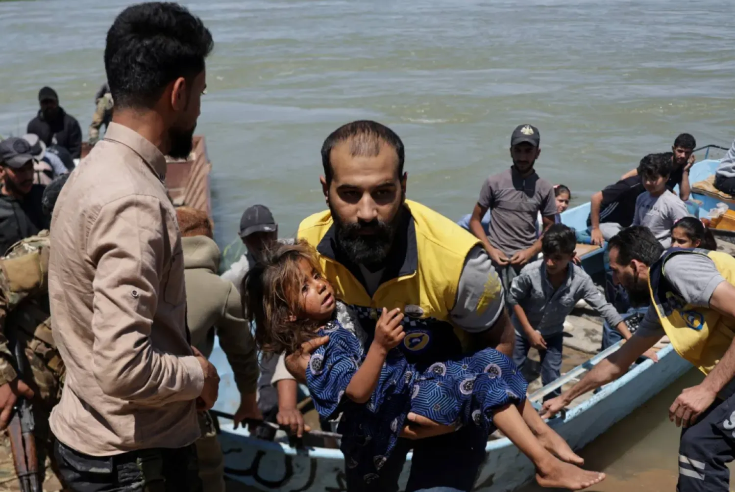 FILE: A member of the Syrian Civil Defense, also known as the White Helmets, carries a child after water levels rise due to increased dam releases following heavy rainfall this year, in Deir Ezzor, Syria, May 30, 2026. REUTERS/Khalil Ashawi
