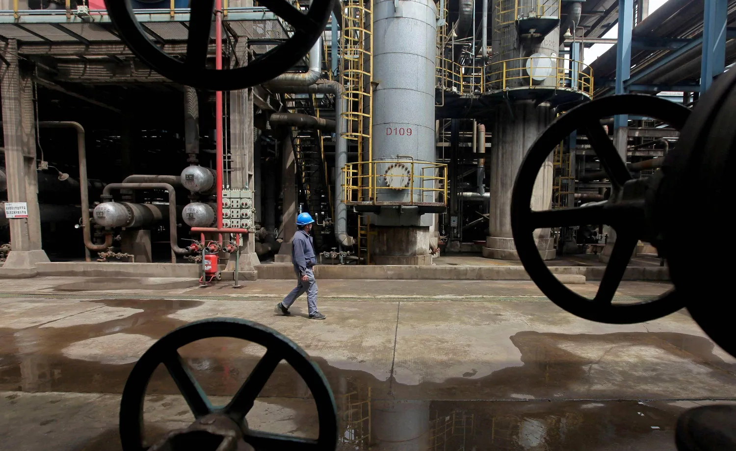 FILE PHOTO: A worker walks past oil pipes at a refinery in Wuhan, Hubei province March 23, 2012.   REUTERS/Stringer/File Photo/File Photo