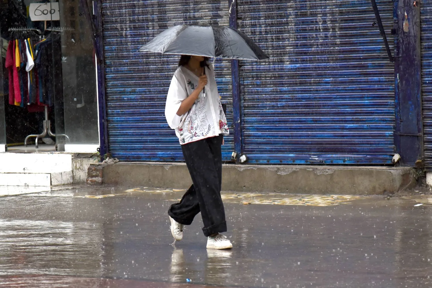 A woman walks along a road amid heavy monsoon rain in Lahore, Pakistan, 12 July 2026. EPA/A. HUSSAIN
