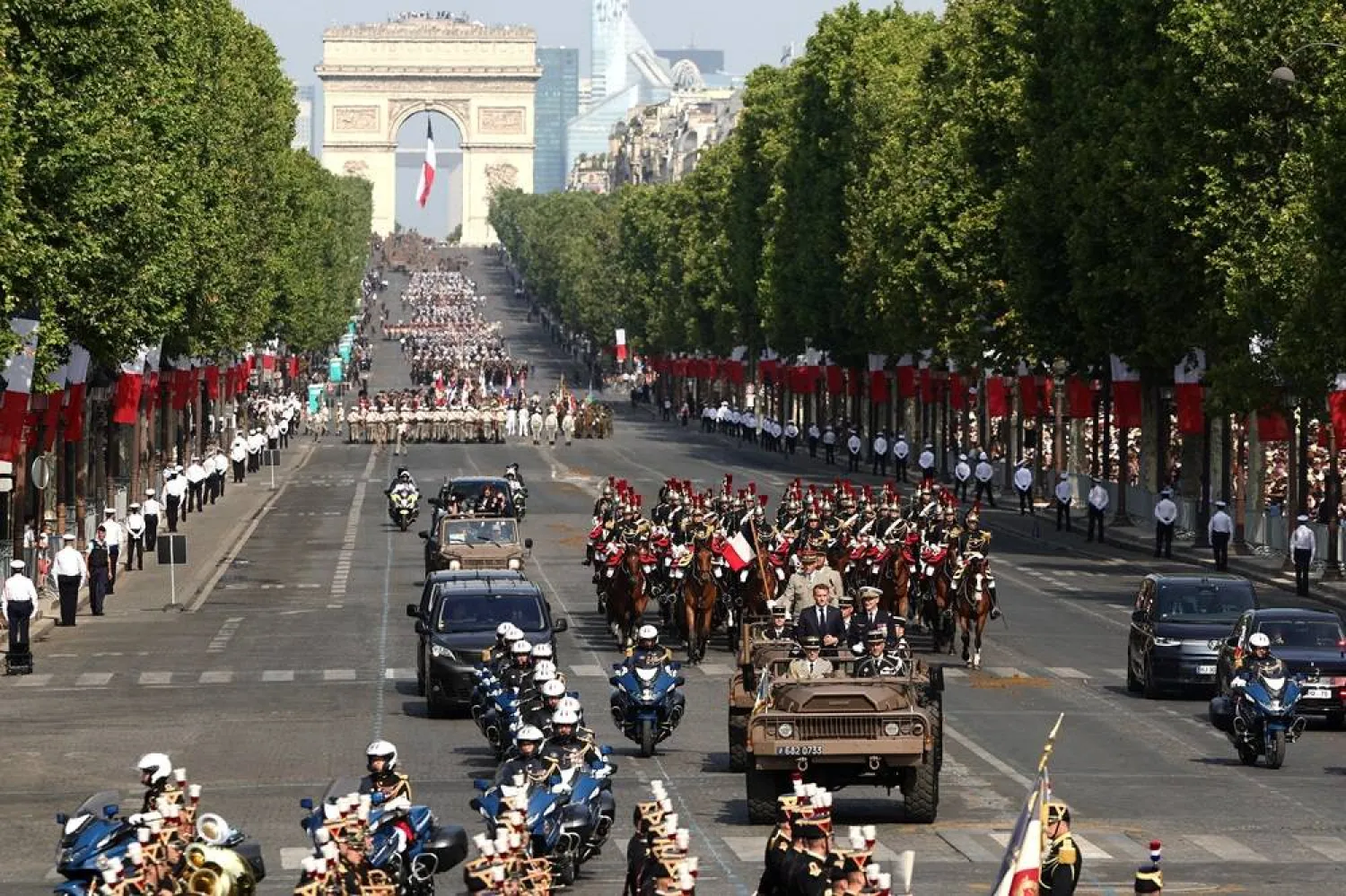 President Emmanuel Macron (C-L) arrives aboard a Light Reconnaissance and Support Vehicle (VLRA), accompanied by French Republican Guards, on Champs-Elysees Avenue during the Bastille Day military parade, in Paris, France, 14 July 2026. (EPA)