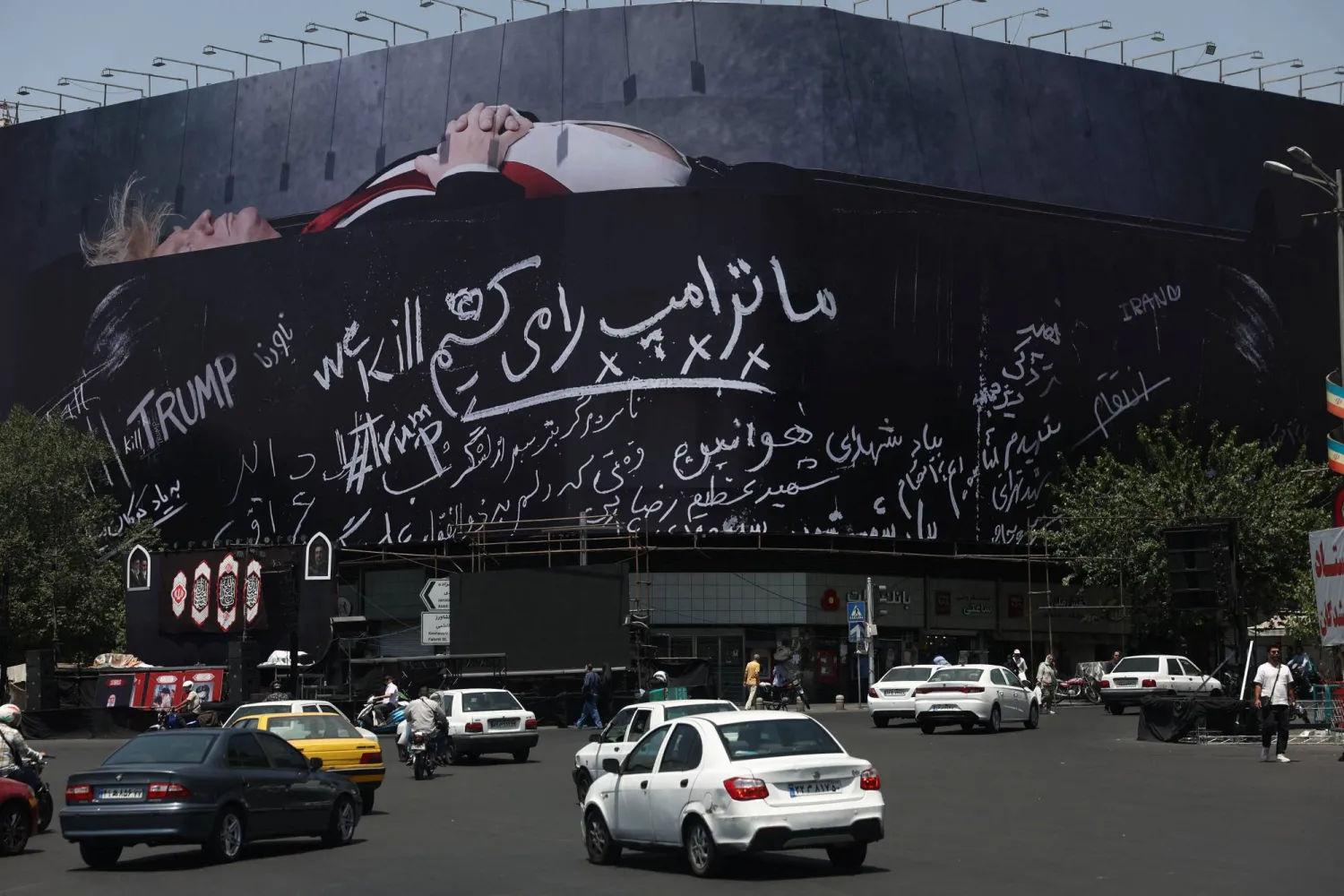  لوحة دعائية على مبنى في طهران تُظهر الرئيس الأميركي داخل نعش وعليها شعار بالفارسية نحن «نقتل ترمب» (رويترز)