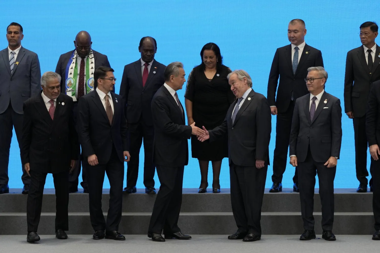وزير الخارجية الصيني وانغ يي يصافح أنطونيو غوتيريش الأمين العام للأمم المتحدة قبيل التقاط صورة جماعية للموقّعين على اتفاق إنشاء «المنظمة ​العالمية للتعاون في مجال الذكاء الاصطناعي» (إ.ب.أ)