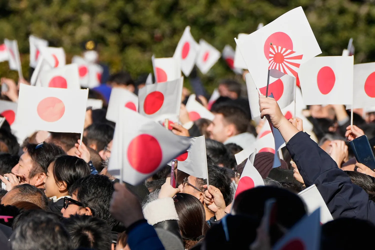 FILE -Well-wishers wave Japanese flags as Emperor Naruhito with his imperial families makes a public appearance at the balcony of Imperial Palace, Jan. 2, 2026, in Tokyo. (AP Photo/Eugene Hoshiko, File)