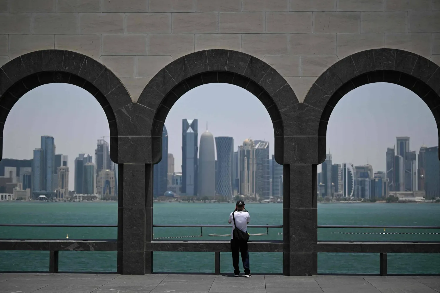 A visitor to the Museum of Islamic Art takes pictures of the skyline of highrise buildings in Doha on July 9, 2026. (AFP)