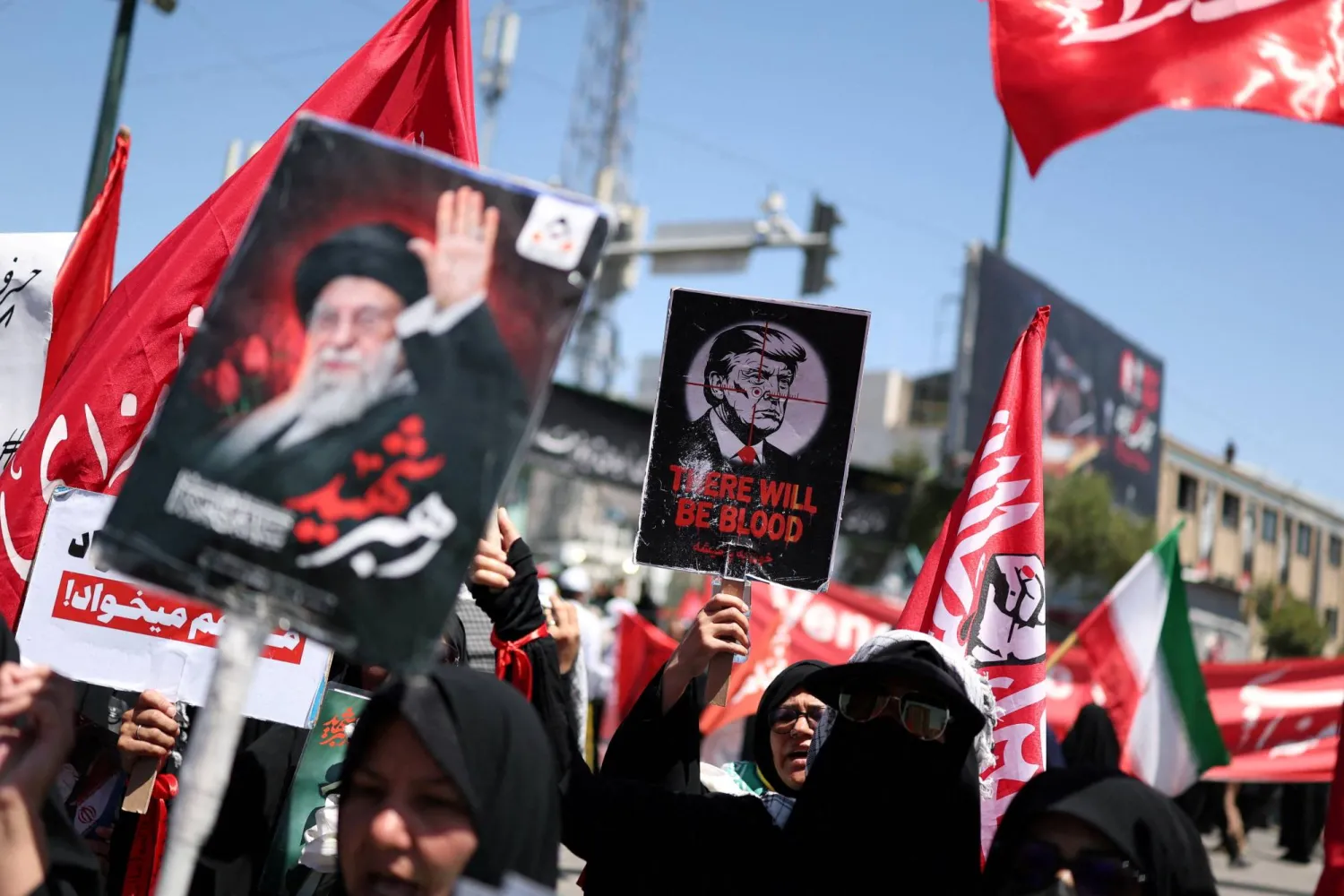 A woman holds a sign depicting US President Donald Trump as mourners gather on the day of the burial of Iran's late Supreme Leader Ali Khamenei, who was killed on February 28 in Israeli and US airstrikes, in Mashhad, Iran, July 9, 2026. REUTERS