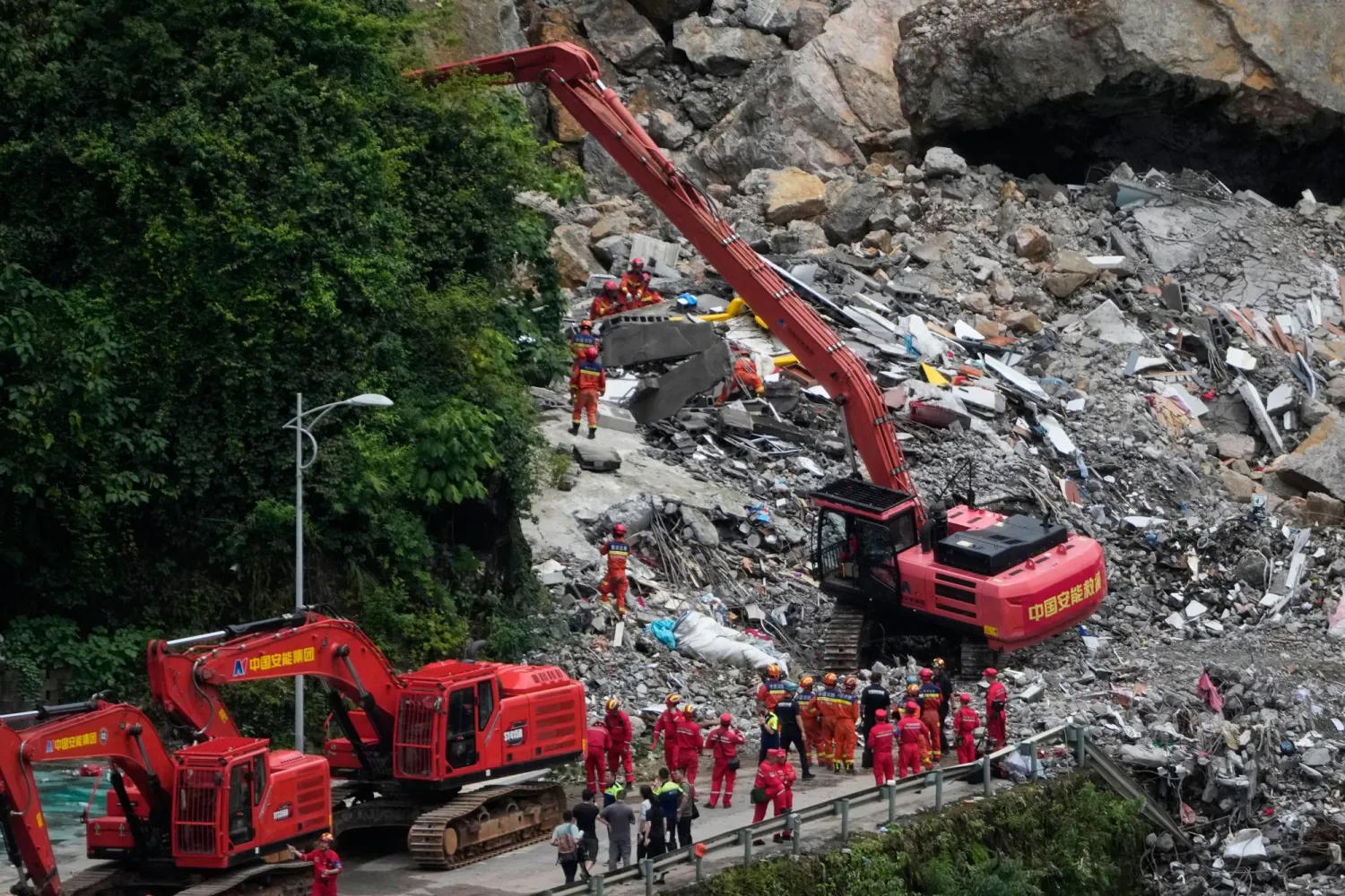 Rescuers use a heavy duty machine to clear the rubble to search for trapped victims at the scene of a landslide in Pengshui County in southwestern China's Chongqing on Saturday, July 18, 2026. (AP Photo/Andy Wong)
