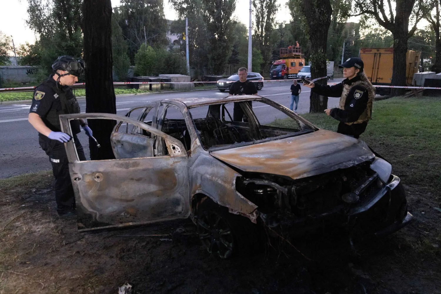 17 July 2026, Ukraine, Kharkiv: Ukrainian police officers examine a charred vehicle following a russian 'banderol' missile strike on a road in Kharkiv's Shevchenkivskyi district. Photo: Yevhen Titov/ZUMA Press Wire/dpa