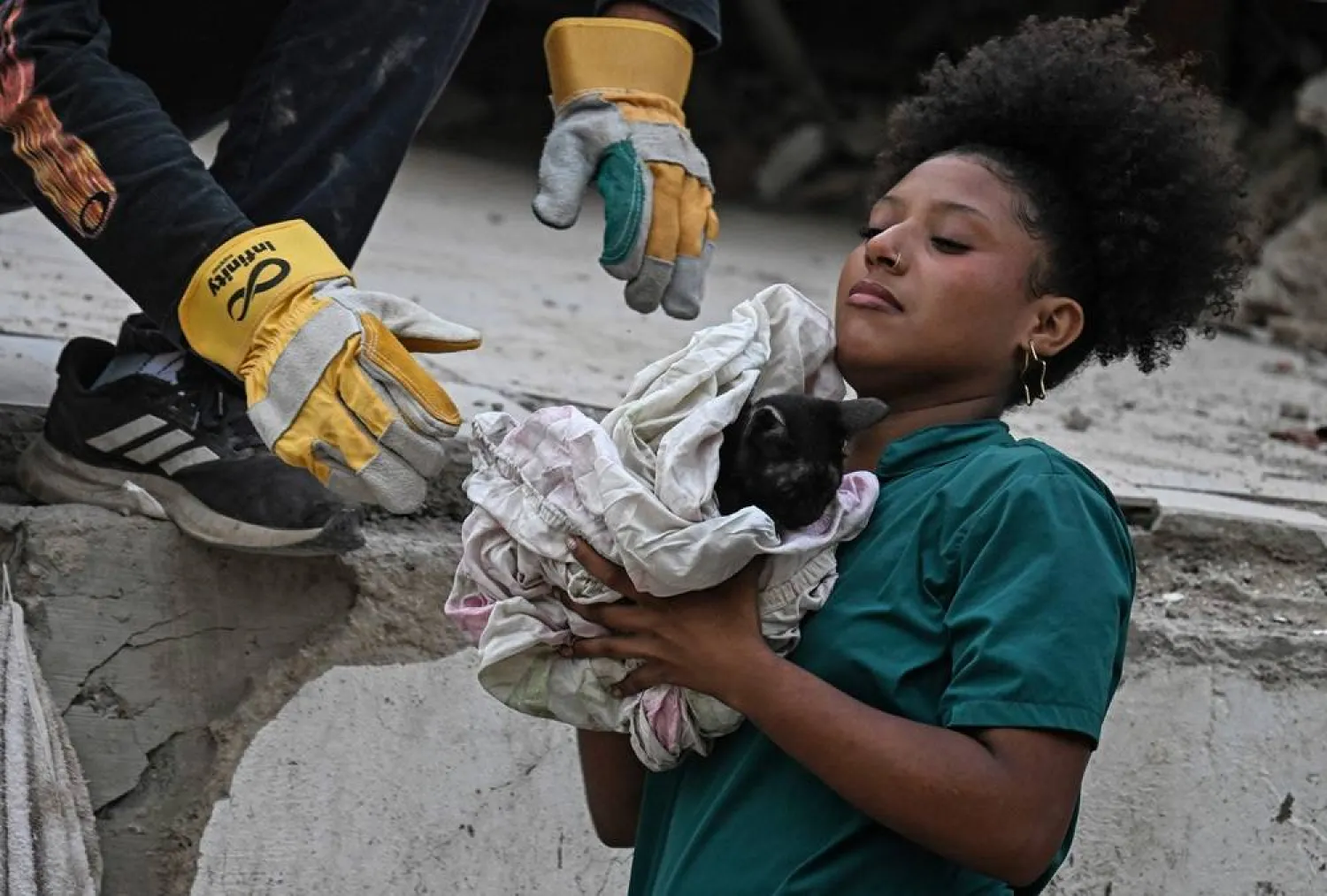 A volunteer rescuer holds a cat after pulling it out from under the rubble of a building damaged by the June 24 earthquakes, in Caraballeda, state of La Guaira; Venezuela, on July 18, 2026. (AFP)
