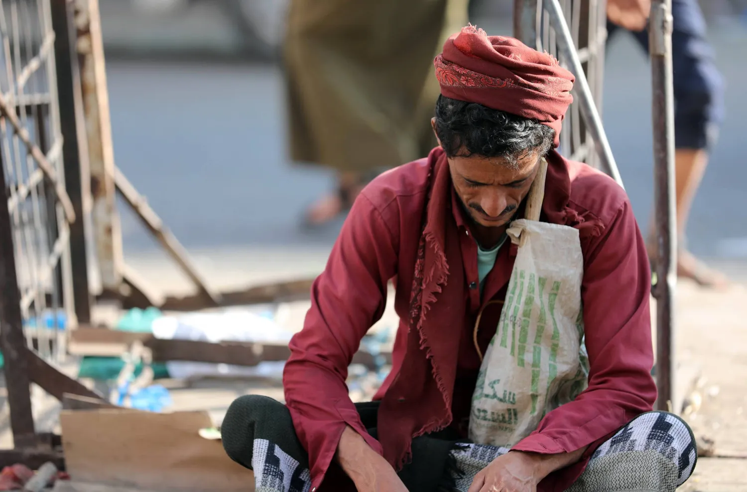 عامل بناء يمني في تعز يجلس منتظراً من يطلب منه العمل بالأجر اليومي (أ.ف.ب)