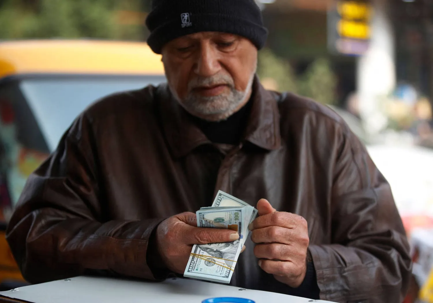 رجل يعدّ أوراقاً نقدية من فئة الدولار الأميركي في سوق الكفاح ببغداد في 27 ديسمبر 2022 (أ.ف.ب)