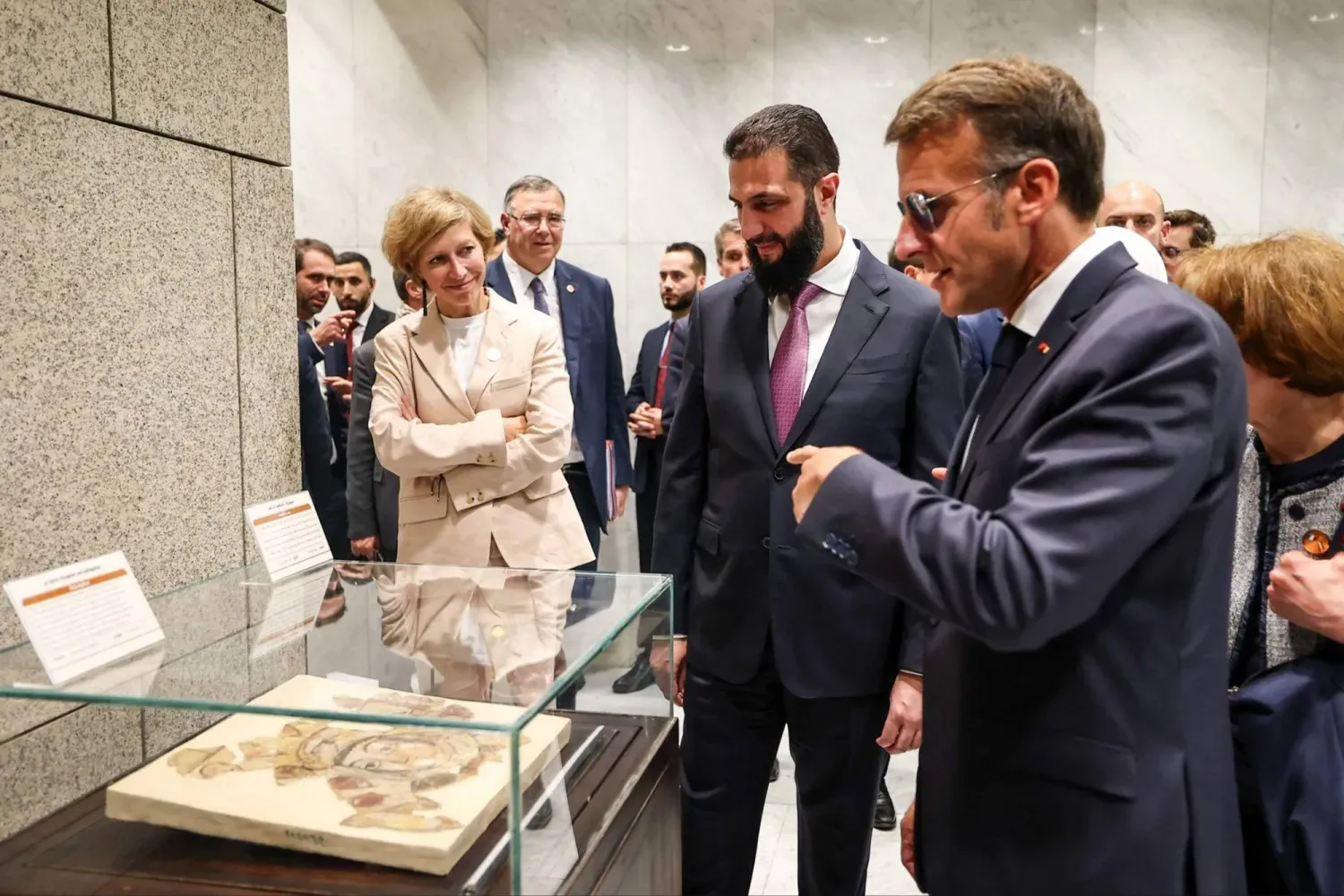 Suriye Devlet Başkanı Ahmed eş-Şara ve Fransa Cumhurbaşkanı Emmanuel Macron, 7 Temmuz 2026'da Şam'daki Halk Sarayı’nda düzenlenen resmi sergi sırasında, 2010'dan bu yana Paris'teki Arap Dünyası Enstitüsü’ne ödünç verilen Suriye'ye ait tarihi eserleri inceliyor (SANA).