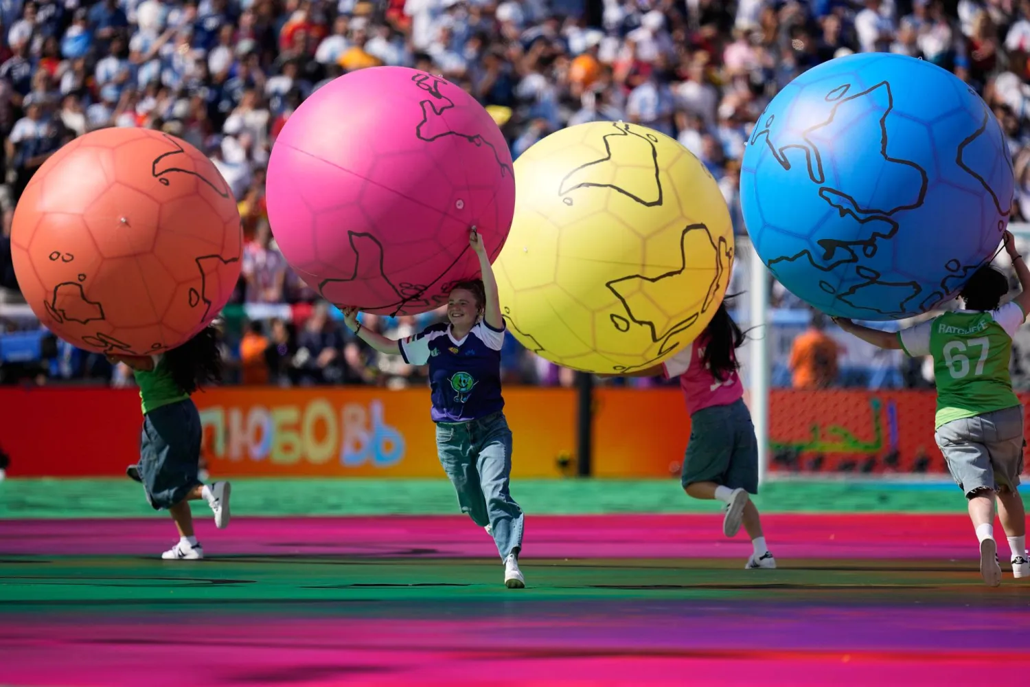أطفال يركضون على أرضية الملعب خلال عرض الاستراحة بين شوطي نهائي كأس العالم بين إسبانيا والأرجنتين (أ.ب)
