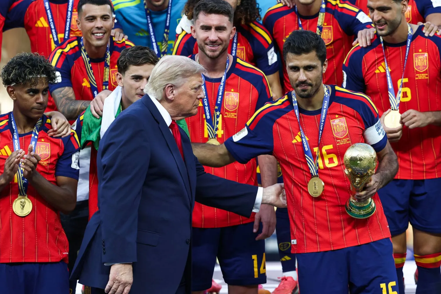 لم يغادر ترمب المنصة كما جرت العادة بل بقي واقفاً إلى جانب لاعبي إسبانيا أثناء لحظة رفع الكأس (أ.ف.ب) 