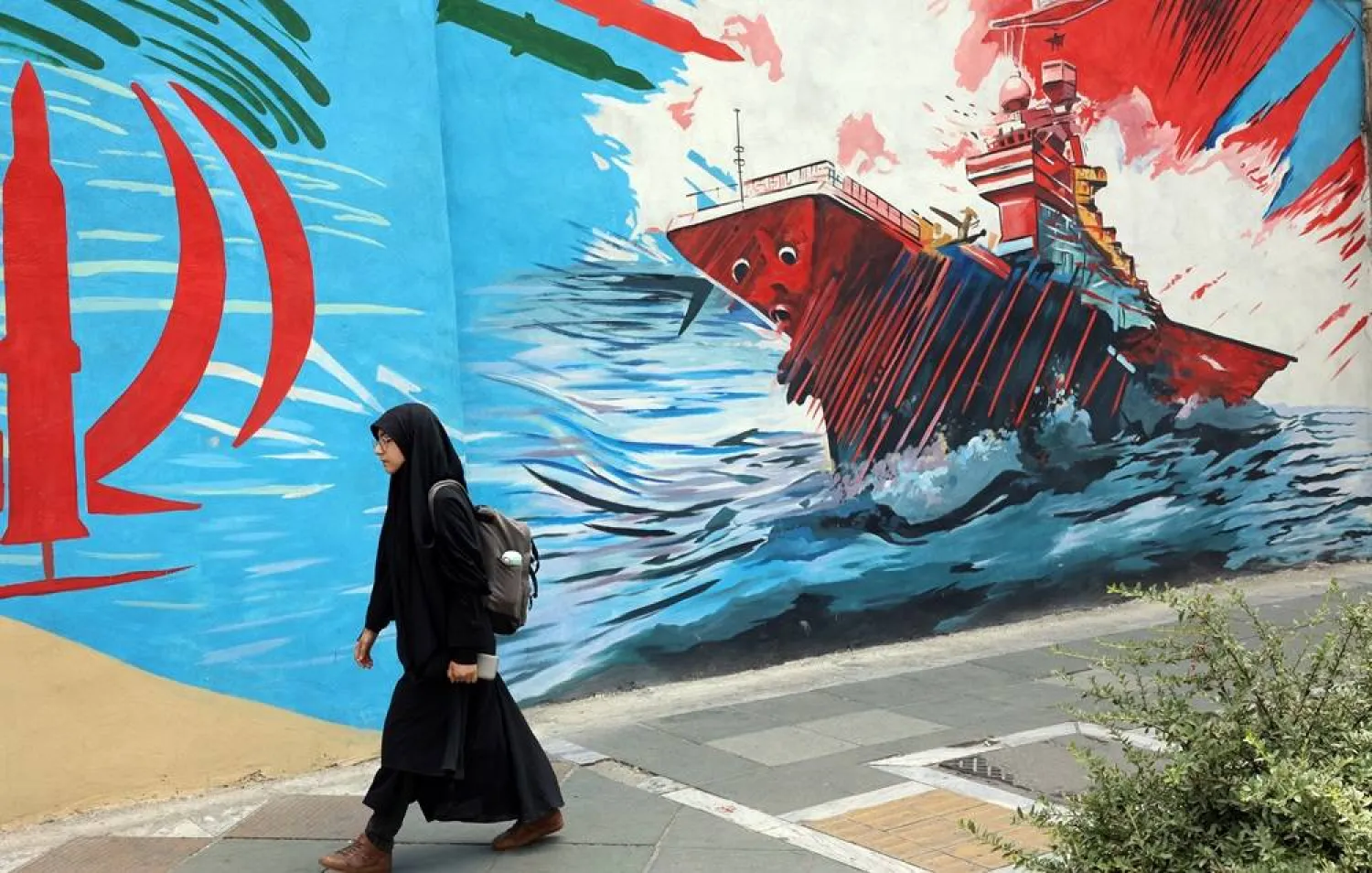 A woman walks next to anti-US graffiti on a street in Tehran, Iran, 20 July 2026. (EPA)