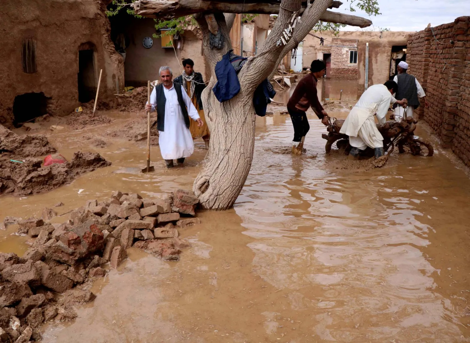 سكان ينتشلون أغراضاً من منزل دمّره الفيضان في منطقة إنجيل بولاية هرات بأفغانستان (أرشيفية - رويترز)