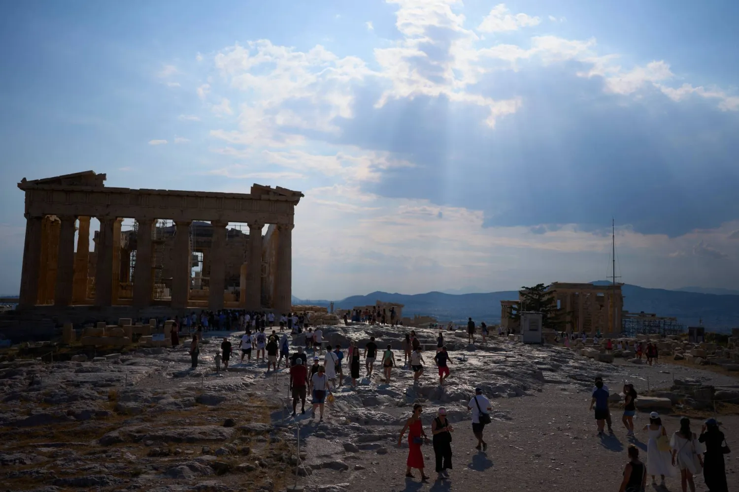 FILE - Sun rays break through the clouds above the ancient Parthenon temple as tourists walk across the Acropolis during a hot day in Athens, Thursday, July 2, 2026. (AP Photo/Petros Giannakouris, File)