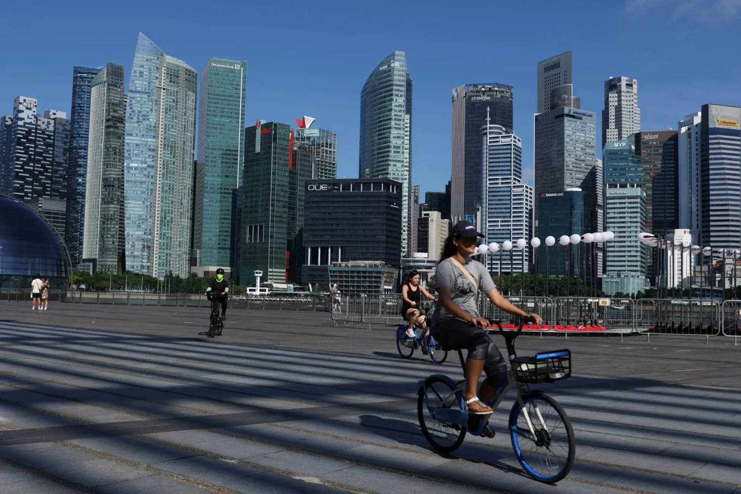 FILE PHOTO: People ride bikes past the skyline of the central business district in Singapore, June 13, 2025. REUTERS/Edgar Su/File Photo