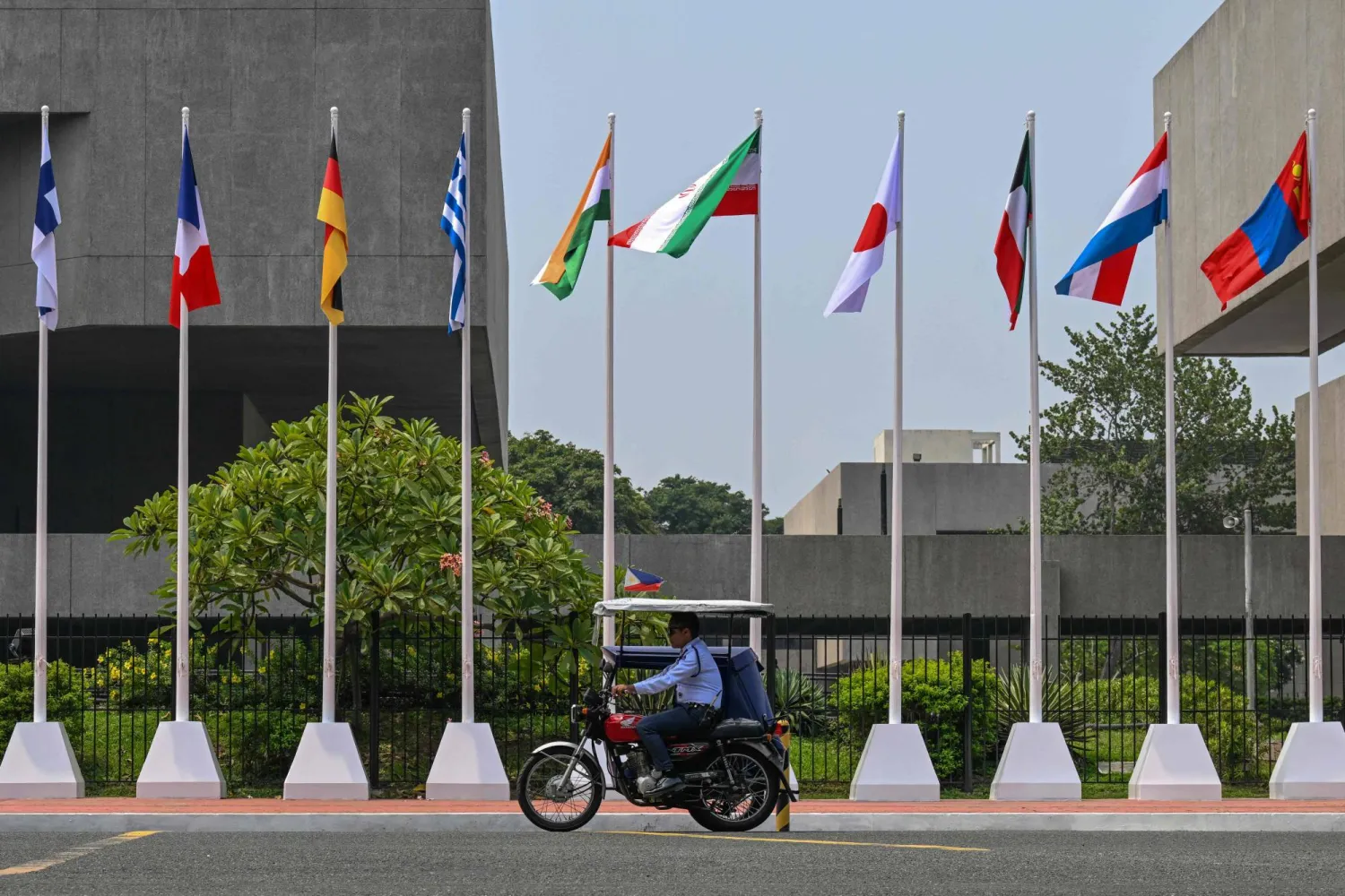  A man rides past flags of ASEAN member states seen outside the venue of the 59th Association of Southeast Asian Nations (ASEAN) Foreign Ministers' Meeting and Related Meetings in Pasay, Metro Manila on July 21, 2026. (AFP) 
