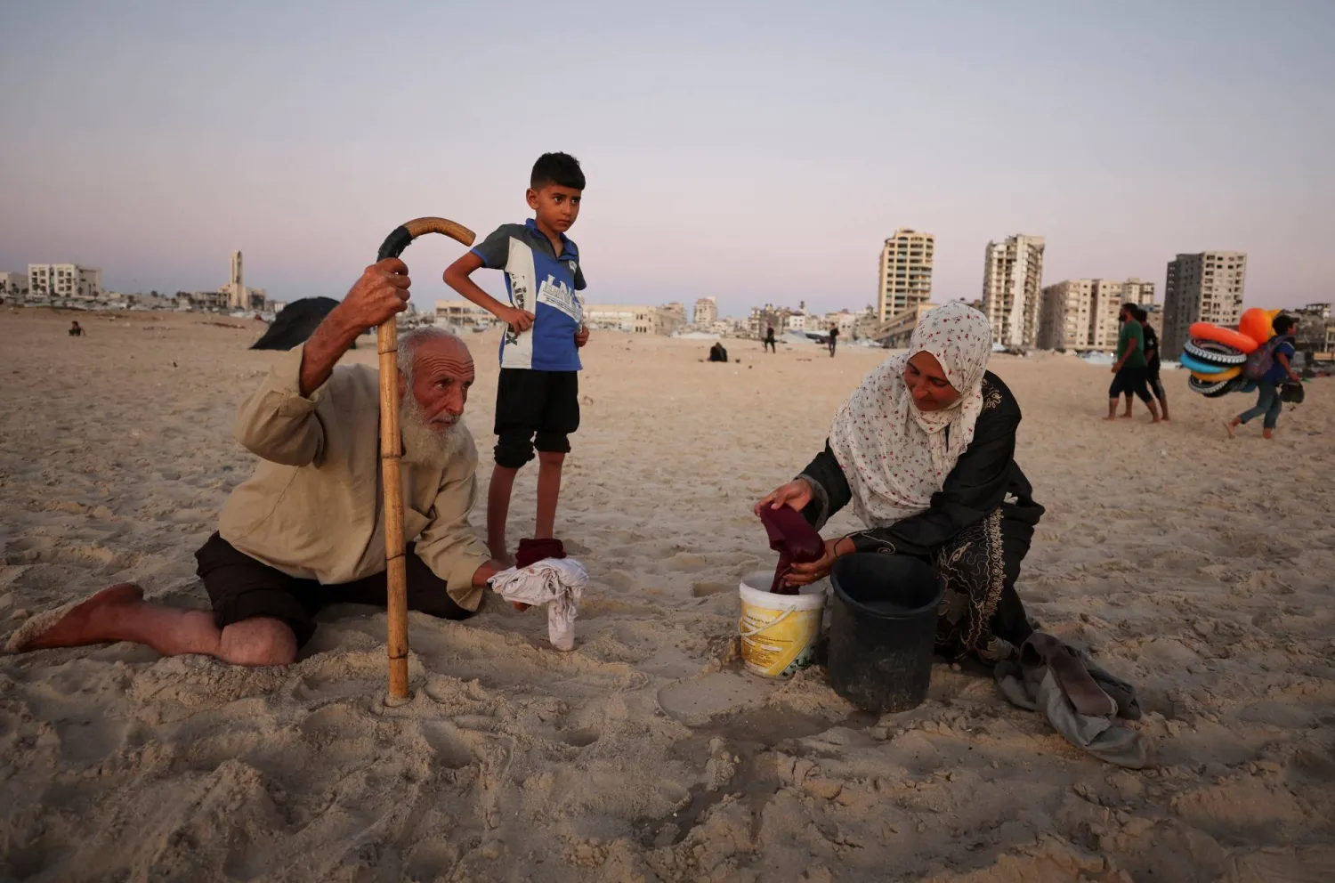 امرأة فلسطينية نازحة تغسل ملابسها على شاطئ البحر الأبيض المتوسط ​​في مدينة غزة (رويترز)