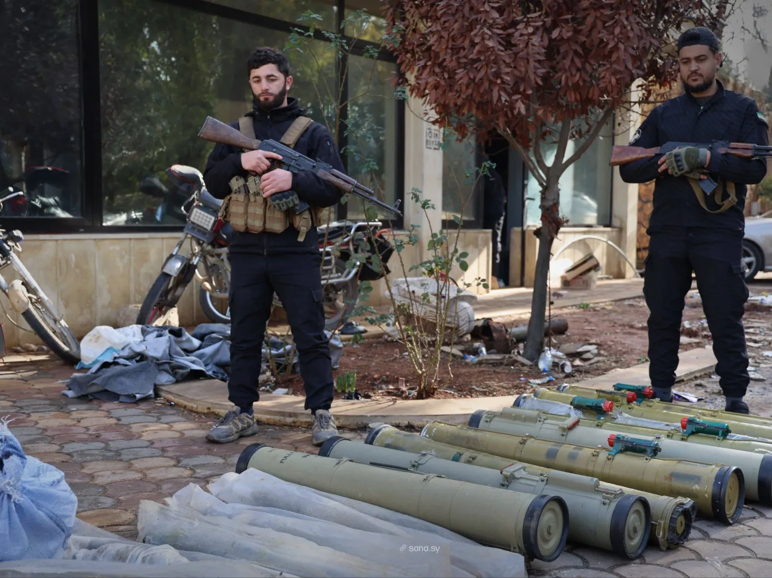Syrian security forces personnel stand next to a weapons shipment prepared for smuggling to Lebanon. (SANA file)