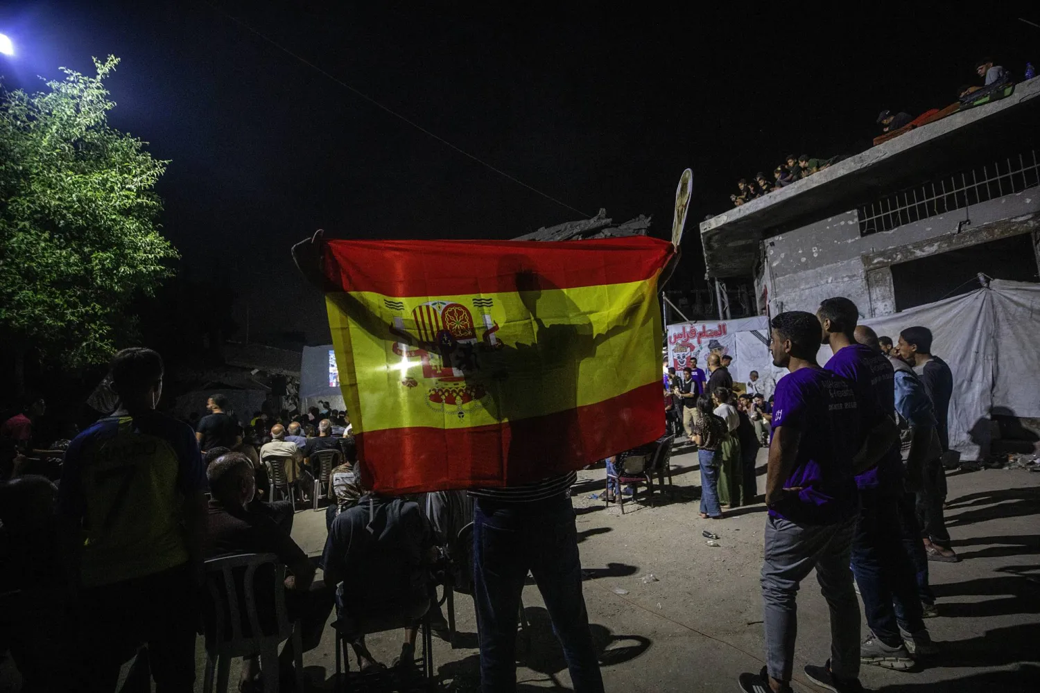 فلسطيني يرفع علم إسبانيا في أثناء متابعة نهائي كأس العالم شمال غزة (إ.ب.أ)
