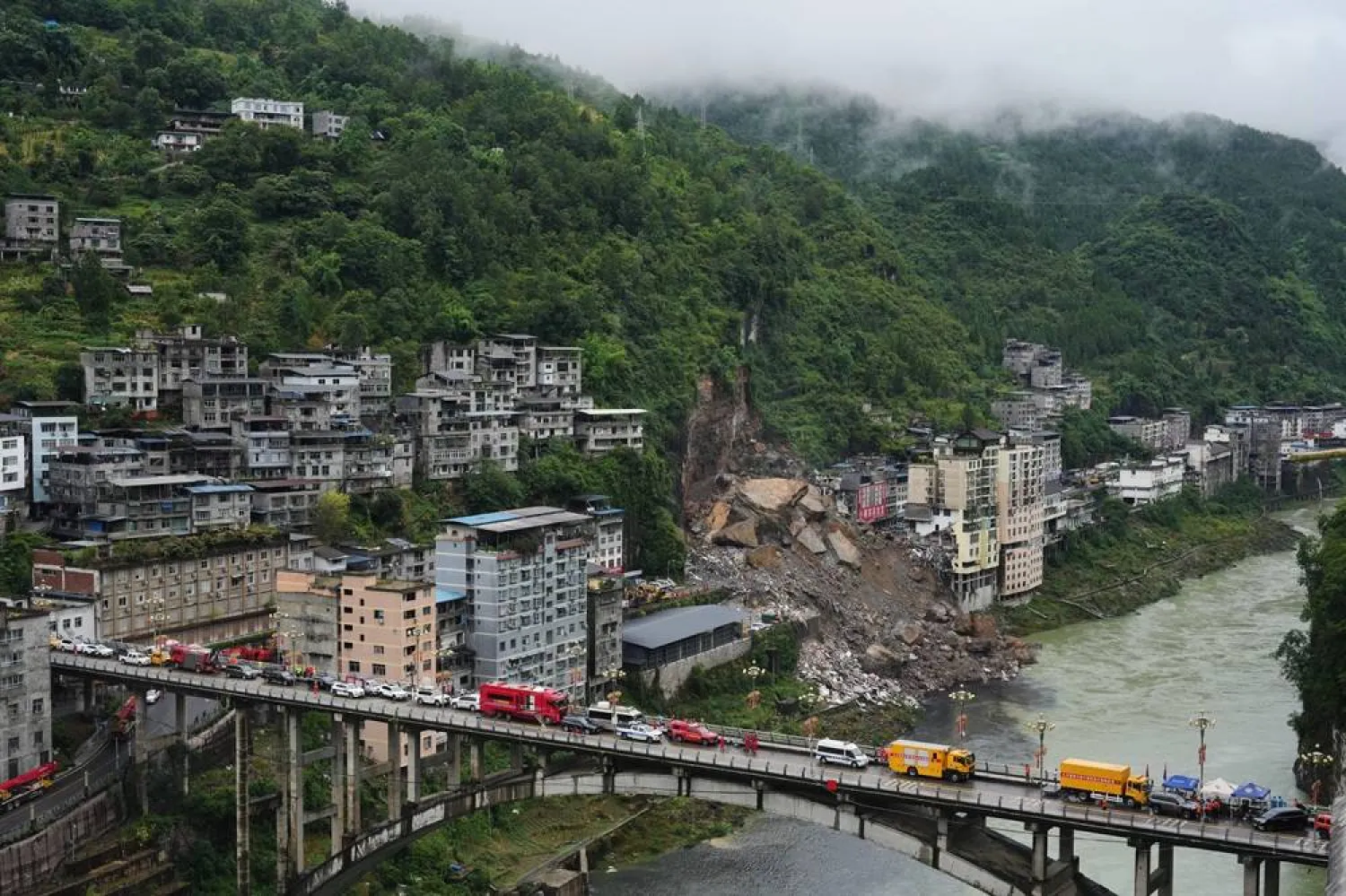  Rescue vehicles stand by on the bridge as rescuers conduct a search and rescue operation at the scene of a landslide in Pengshui County in southwestern China's Chongqing on Saturday, July 18, 2026. (AP) 