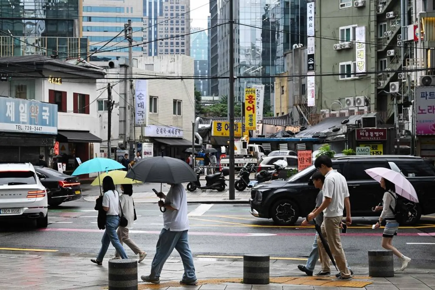 People carry umbrellas as they walk along a sidewalk in Seoul on July 21, 2026. (AFP)