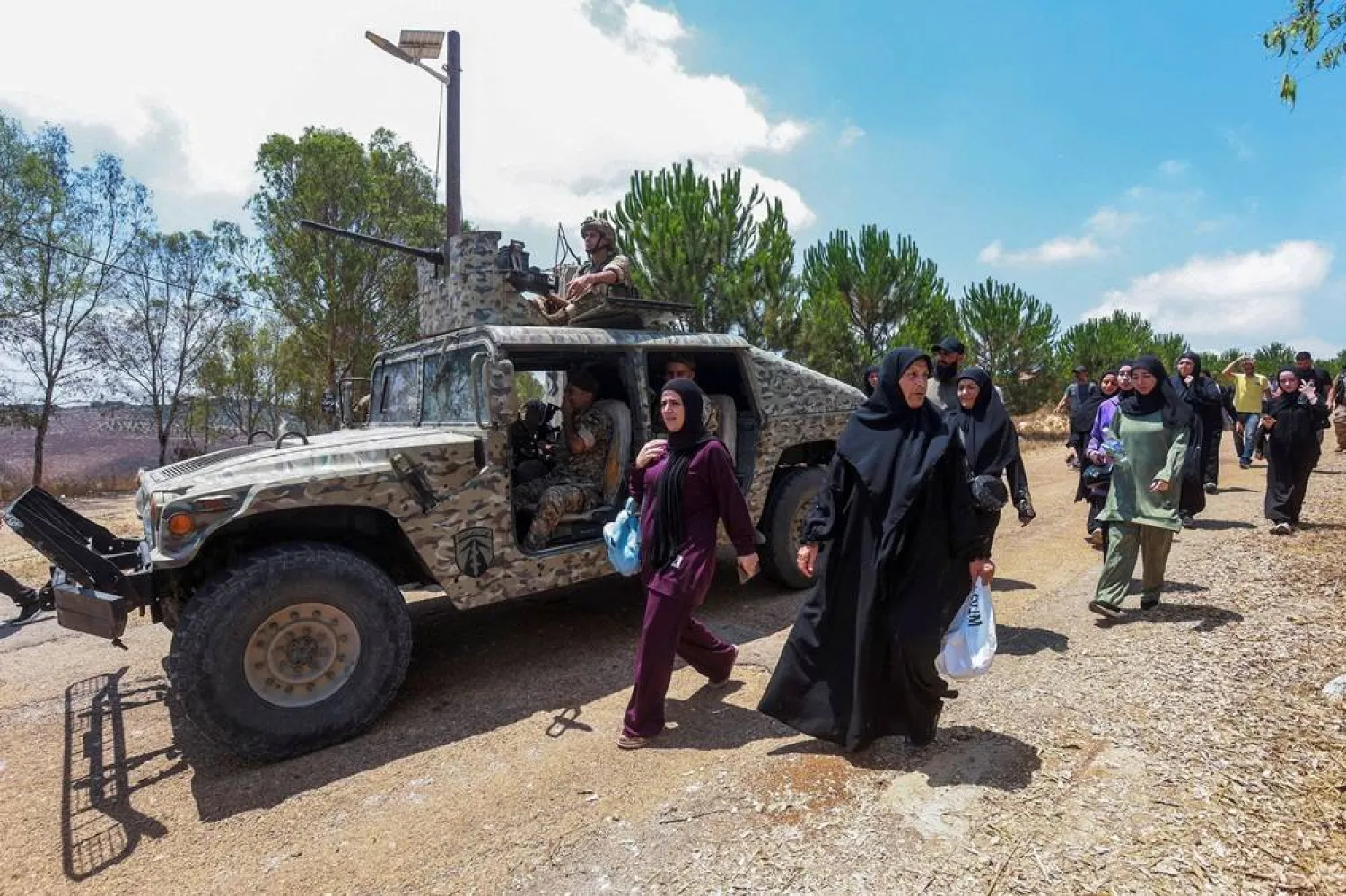 People walk next to a military vehicle as residents attempt to enter Zawtar al-Gharbiya village, as members of the Lebanese military block the road, in Zawtar al-Gharbiya, Lebanon July 22, 2026. (Reuters)