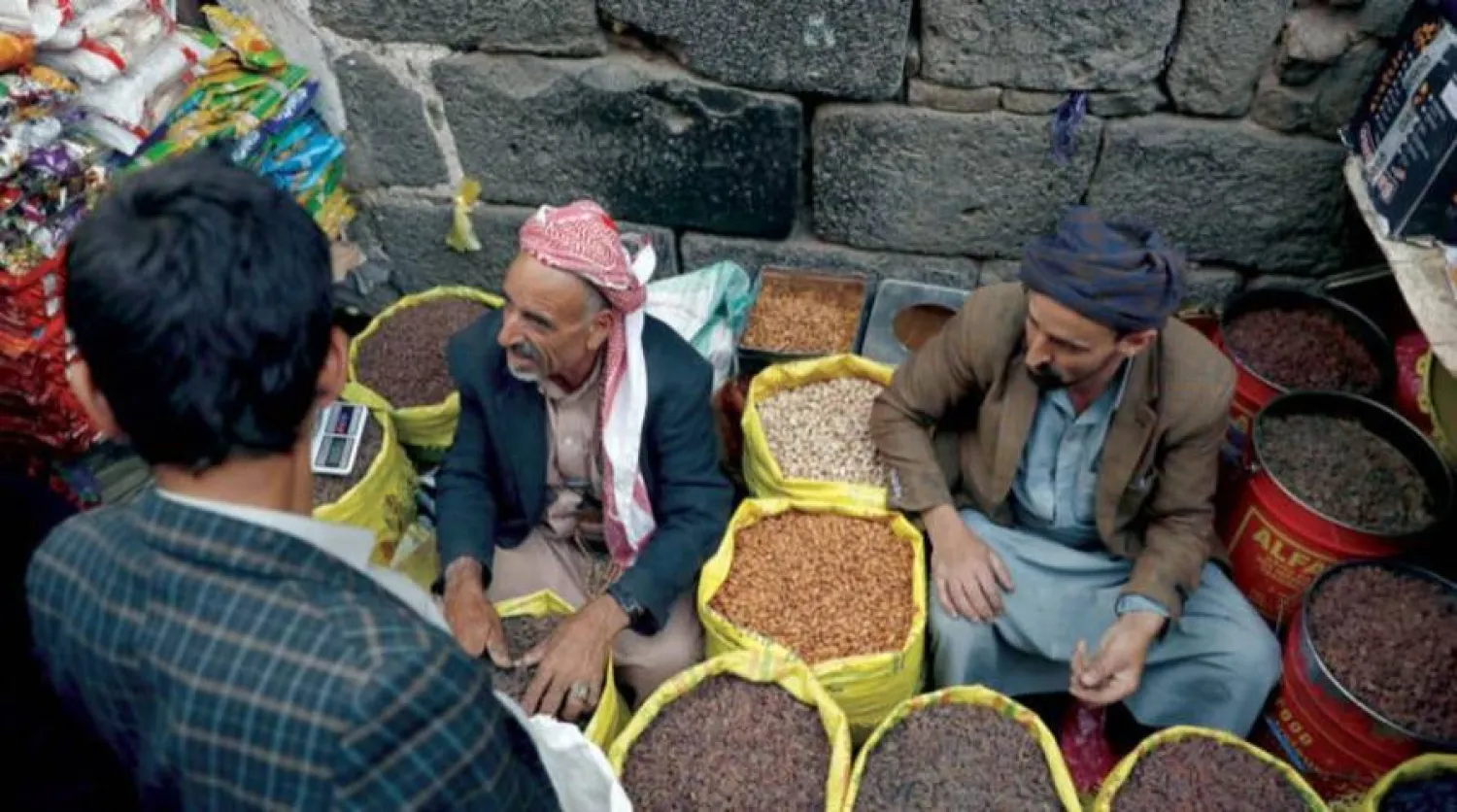 بائعان يستقبلان زبوناً في سوق وسط صنعاء حيث العاصمة اليمنية الخاضعة للحوثيين (إ.ب.أ)
