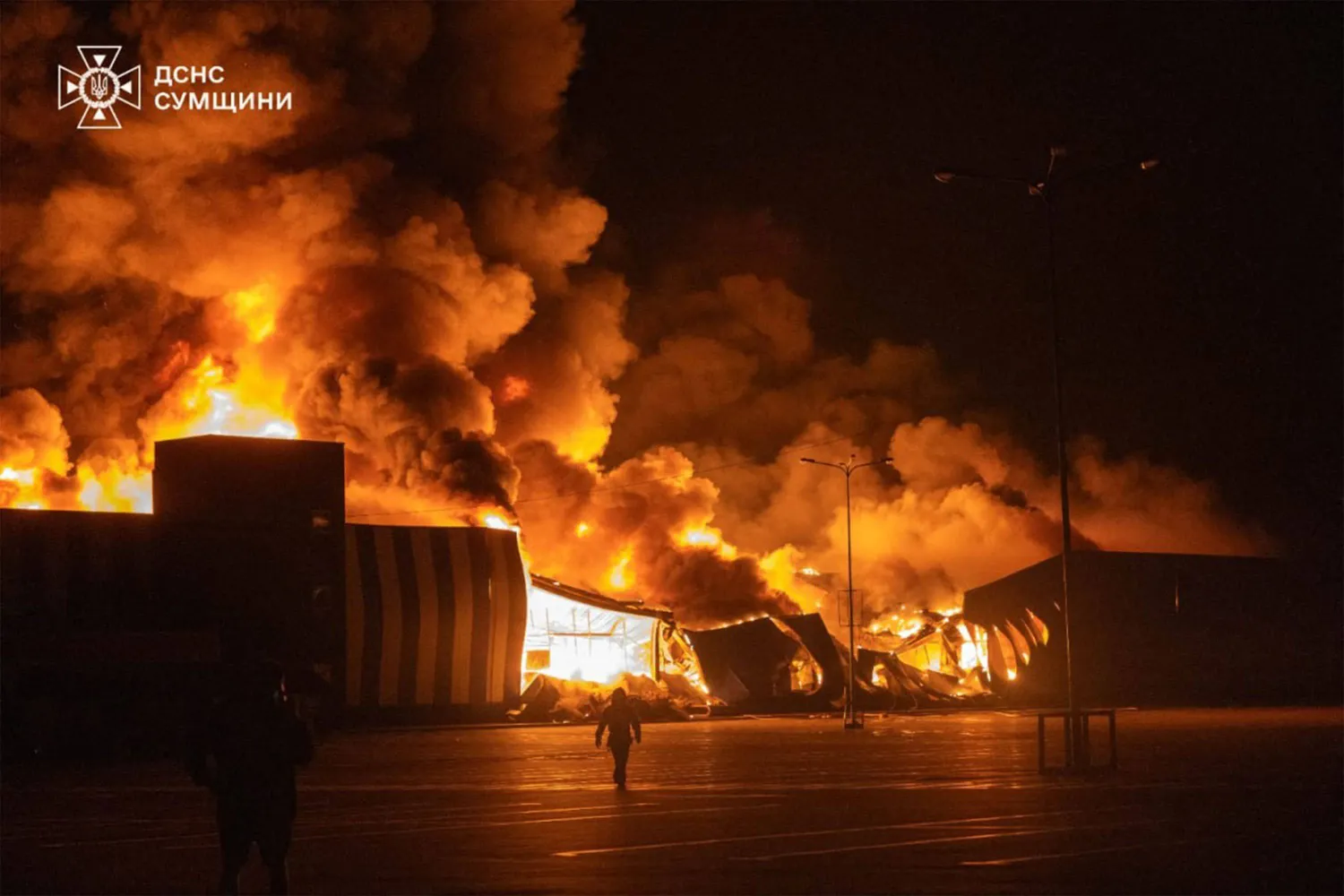 TOPSHOT - This handout photograph taken and released by the State Emergency Service of Ukraine on July 21, 2026, shows firefighters working to extinguish a fire at the site of a drone strike on a shopping center in Sumy, amid the Russian invasion of Ukraine. (Photo by Handout / STATE EMERGENSY SERVICE OF UKRAINE / AFP) 