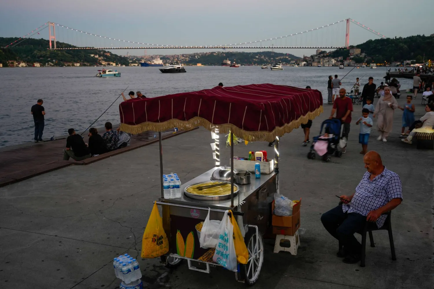 A vendor sells corn on the bank of the Bosphorus Strait at dusk in Istanbul, Turkey, Friday, June 26, 2026. (AP Photo/Emrah Gurel)