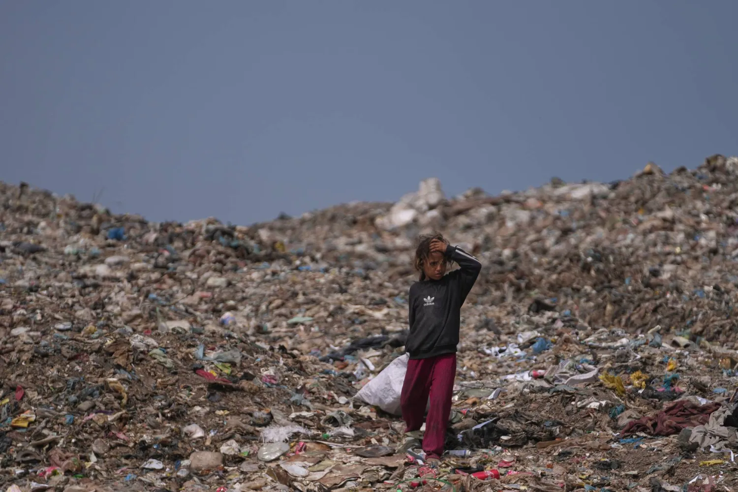 A Palestinian girl searches for reusable items at a landfill in Deir al-Balah, in the central Gaza Strip, Thursday, July 23, 2026. (AP Photo/Abdel Kareem Hana)