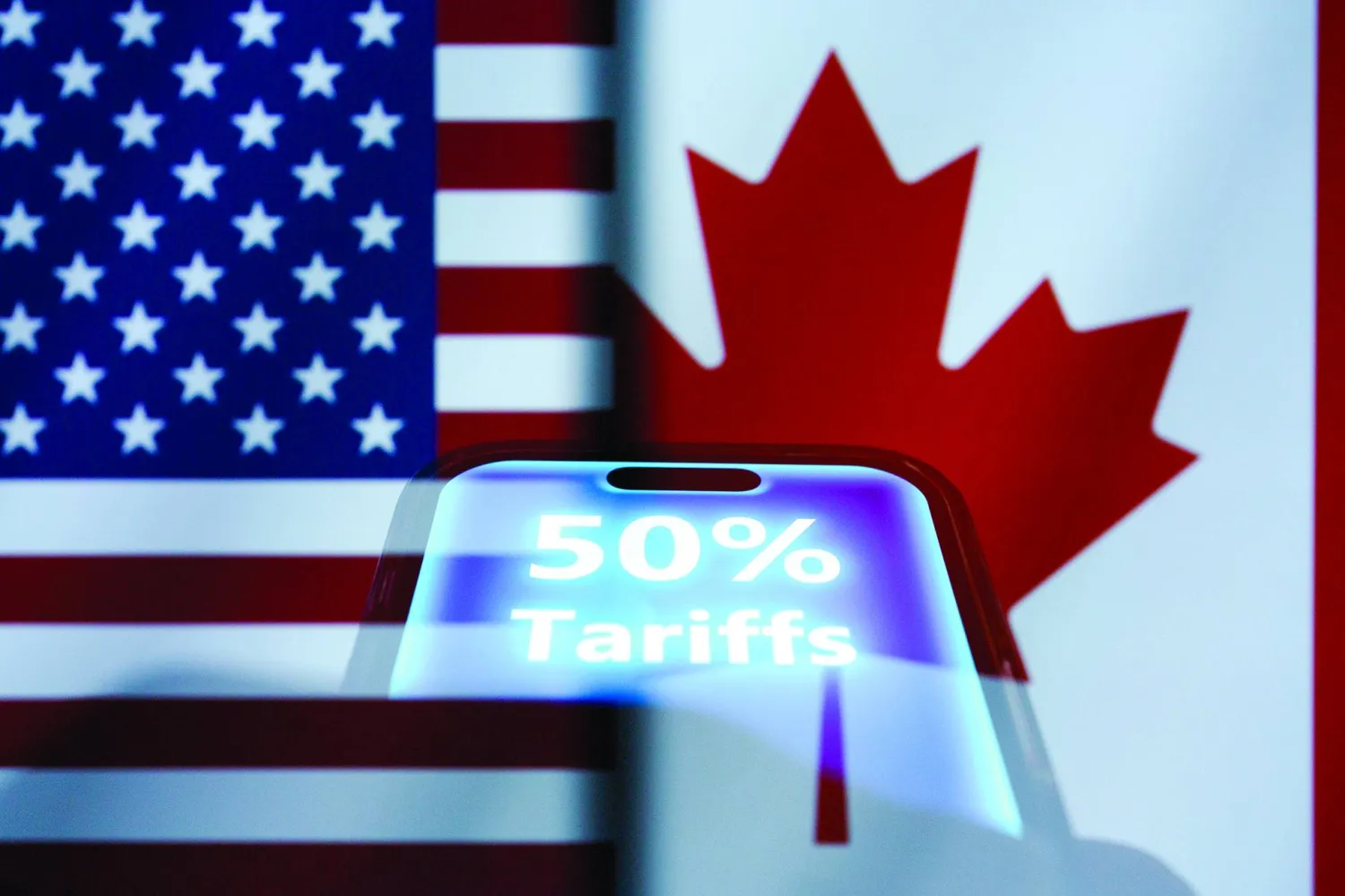 21 July 2026, Taiwan, Taichung: A hand holds a smartphone displaying the term 50 percent tariffs backdropped by cropped flags of the United States and Canada. Photo: Andre M. Chang/ZUMA Press Wire/dpa