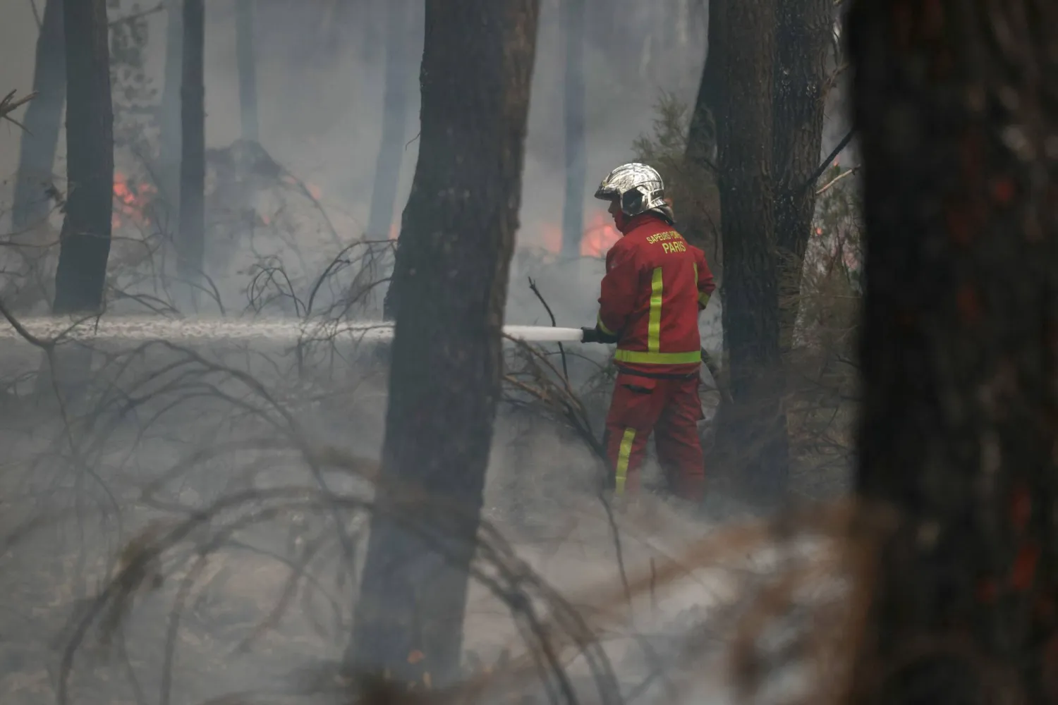 A firefighter of Paris Fire Brigade douses the hotspots in Marcheprime west of Bordeaux on July 26, 2026 as a wildfire has been ravaging the forest north of the Arcachon Basin (Gironde) since July 22. (Photo by Alain JOCARD / AFP)