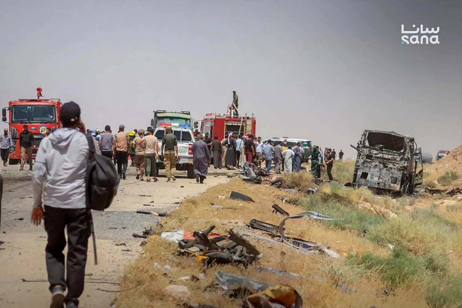 عناصر الدفاع المدني وبعض الأهالي يتفقدون حادث موقع اصطدام حافلتي ركاب على طريق دير الزور - دمشق في 25 يوليو (سانا - أ.ف.ب)