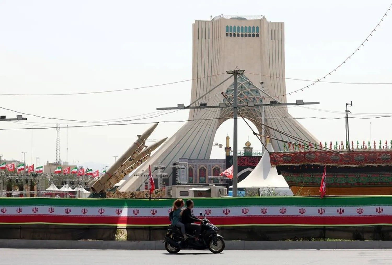An Iranian couple rides a motorbike next to Iranian missiles, Zolfaghar, on display at Azadi Square in Tehran, Iran, 24 July 2026. (EPA)