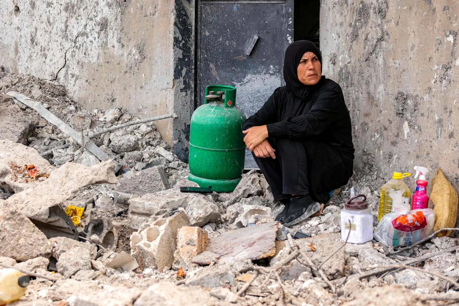 A woman sits next to a cooking gas canister by the rubble of her destroyed house in the village of Zawtar al-Gharbiyeh in southern Lebanon on July 26, 2026. (AFP)